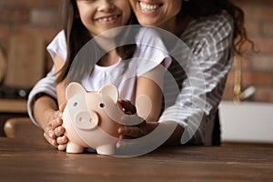 Close up happy mother and daughter holding pink piggy bank