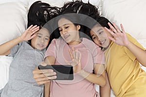 Close up happy mother and her kid making aselfie or video call to father in bed. Family concept mother and her daughter contact