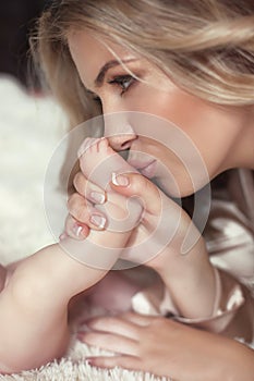 Close-up of happy Mother kissing Baby's feet her Newborn baby gi