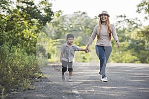 Close up of happy mum and son holding hand in a park.