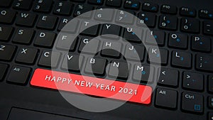 Close-up HAPPY NEW YEAR 2021 spacebar button with red color on a black laptop keyboard background. photo