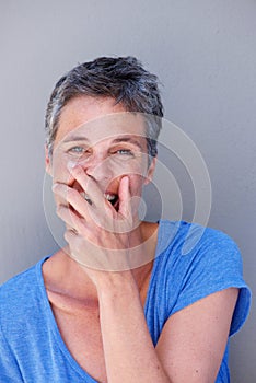 Close up happy older woman laughing with hand covering mouth