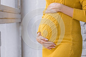 Close up of happy pregnant woman with big belly at window