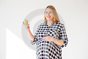 Close up of happy pregnant woman eating green apple at home