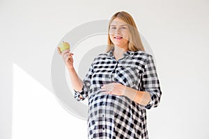 Close up of happy pregnant woman eating green apple at home