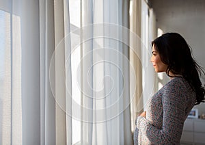 Close up of happy pregnant woman looking to window