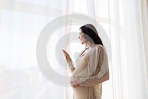 Close up of happy pregnant woman looking to window