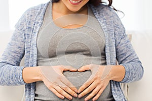 Close up of happy pregnant woman making heart