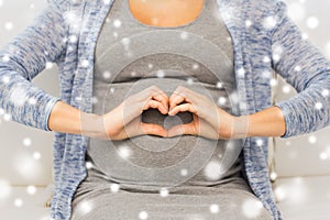 Close up of happy pregnant woman making heart