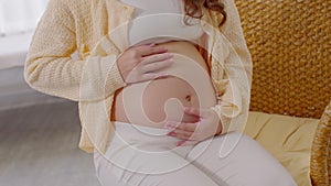 Close up Happy Pregnant Woman sitting on bed holding and stroking her big belly at home,Pregnancy of young woman enjoying with