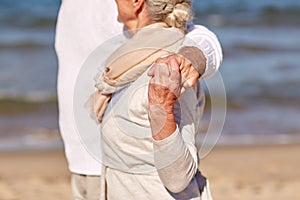 Close up of happy senior couple hugging on beach