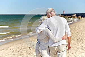 Close up of happy senior couple hugging on beach