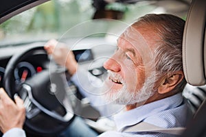 Close-up of happy senior man sitting in car in driver seat, driving.