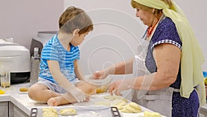 Close up of the happy smiled grandmother and grandson kneading a daugh together. slow motion of an elderly woman and