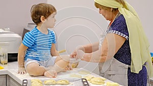 Close up of the happy smiled grandmother and grandson kneading a daugh together. slow motion of an elderly woman and