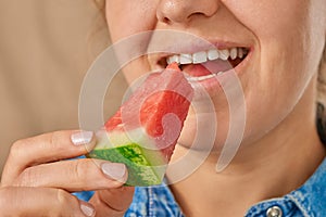 Close-up of a happy smiling Caucasian woman holding a slice of watermelon with her hand. Front three-quarter view