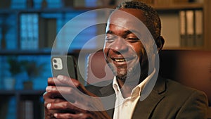 Close-up happy smiling man holding smartphone laughing watching funny video using mobile app on phone in social network