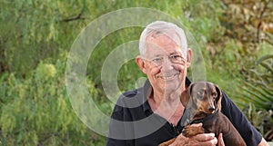 Close-up of a happy, smiling senior man holding his cute little dog