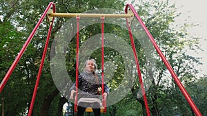 Close up Happy and smiling Teen girl riding a swing. Girl having fun swinging on wooden swing in park. Leisure activity