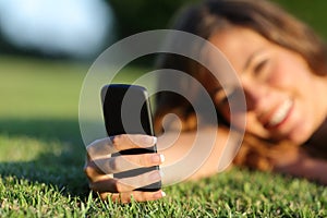 Close up of a happy teen girl hand using a smart phone on the grass