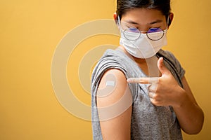 Close up of happy teens girls and wear a mask in the shoulder with plaster on arm after vaccination on yellow studio background,
