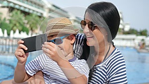 Close-up happy travel family laughing taking selfie using smartphone near swimming pool