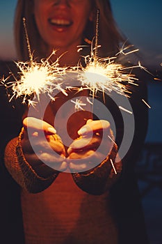 Close-up of happy woman with bright bruning sparklers in the night photo