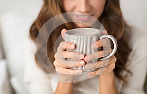 Close up of happy woman with cup of coffee at home