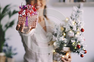 Close up of happy woman giving christmas gift on camera. Focus on decorated present for xmas holiday celebration. Sharing and