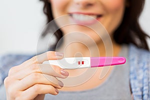 Close up of happy woman with home pregnancy test