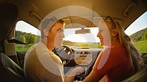 CLOSE UP: Happy woman and man looking into each other\'s eyes while driving.