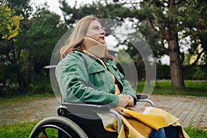 Close-up of a happy woman with a neck brace sitting on wheelchair outdoors