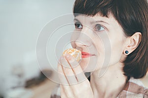 Close up happy woman sniffing citrus fruit and smelling aroma tangerine. Female inhaling mandarine