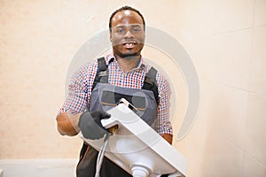 Close-up Of Happy Young African Male Plumber Repairing Sink In Bathroom