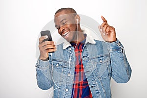 Close up happy young black guy listening to music with smart phone and earphones and dancing