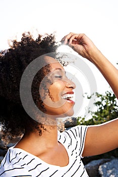 Close up happy young black woman with curly hair smiling outdoors