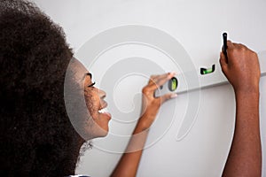 Close up happy young black woman drawing straight line on wall