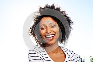 Close up happy young black woman laughing outdoors against bright sunshine