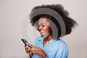 Close up happy young black woman laughing at text message on cellphone