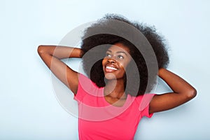 Close up happy young black woman smiling with hands behind head against blue background