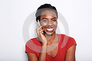 Close up happy young black woman talking on phone by white background