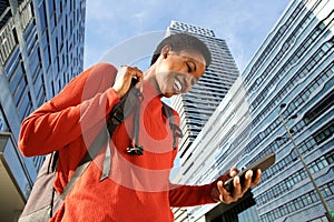 Close up happy young black woman walking in city and looking at mobile phone