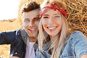 Close up of a happy young couple sitting at the wheat field