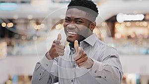 Close-up happy young handsome african american man looking at camera smiling posing showing gesture hey you pistols