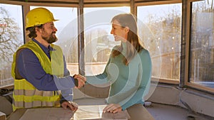 CLOSE UP: Happy young woman and contractor shake hands on a sunny morning.