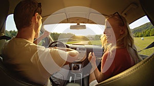 CLOSE UP: Happy young woman and man dance in their car during a scenic cruise.