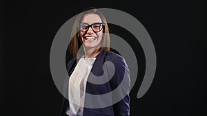 Close up Happy Young Woman, Wearing Eyeglasses, Showing Toothy Smile at the Camera Against Gray Wall Background