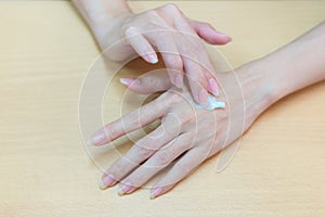 Close-up for hard beautiful woman applying on hand cosmetic cream.