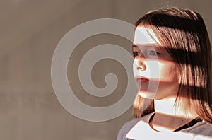 Close up hard light portrait of tween girl with stripe shadows on her face.