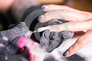 Close-up of hardware milling cutter for removing gel polish. Apparatus manicure in beauty salon. Manicurist with